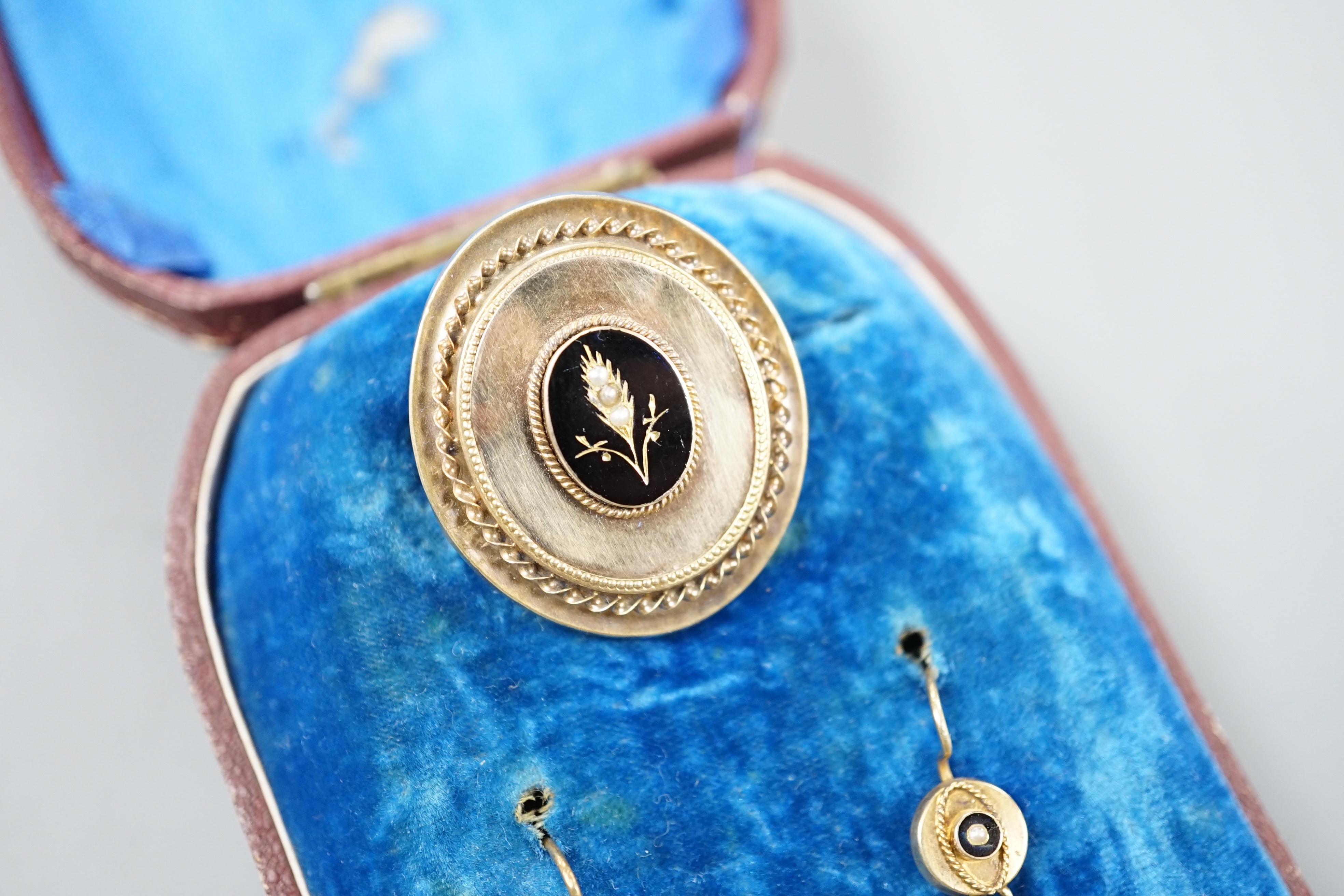 A cased Victorian yellow metal, black enamel and seed pearl set brooch, 35mm and matching pair of drop earrings, gross 13.6 grams.